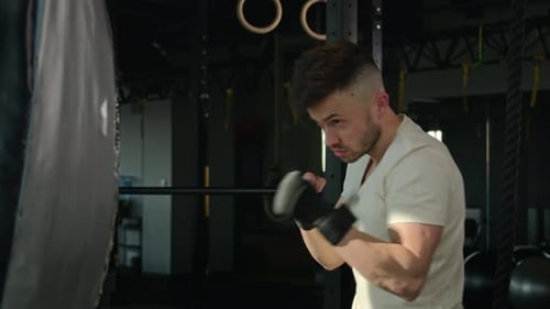 Motivated Caucasian Sportsman Sport Man Boxer Fighter in Gloves Hit Punching Bag in Fitness Gym