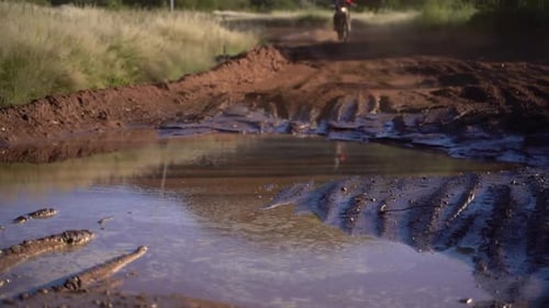Dirt bike rider riding through a puddle of mud