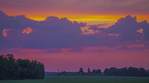 Bunter Sonnenuntergangshimmel mit wogenden Wolken über dem Feld. Zeitraffer