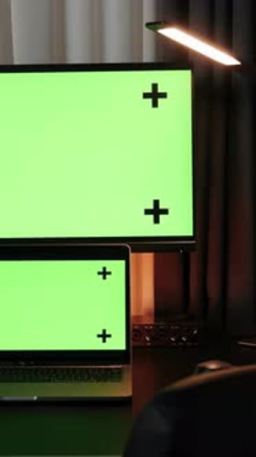 Personal computer and laptop with mock-up green screen monitors. Vertical video