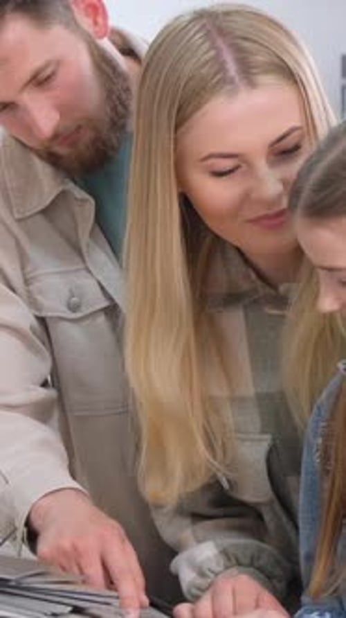 A Young Family in a Hardware Store Chooses a Wooden Laminate Surface for Home Renovation Vertical
