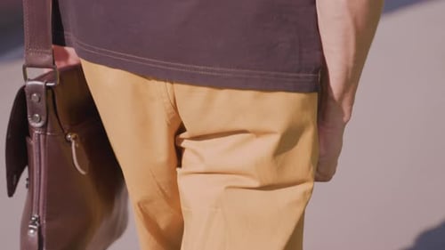 Young Man Walking with Messenger Bag in City