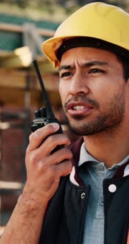 Sitio de construcción, conversando y hombre con radio para comunicarse, recibir comentarios y actualizar