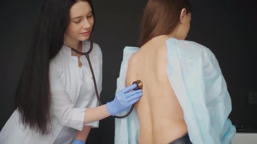 Female Doctor Examining Patient with Stethoscope in Office