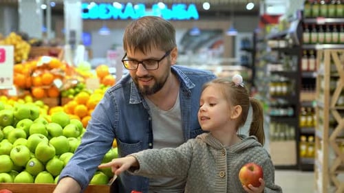Father and Girl Choose Apples in Supermarket Shopping Food in Store