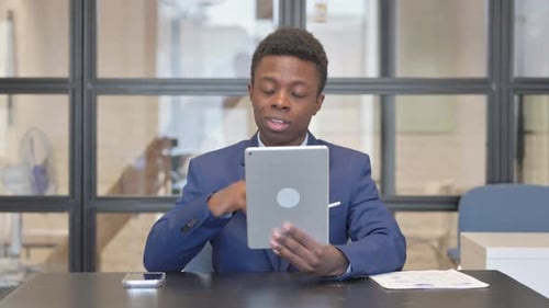 African Woman Doing Video Chat on Tablet in Office