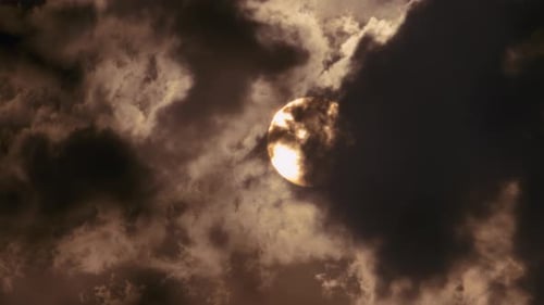 Nahaufnahme einer runden Sonnenscheibe hinter den Wolken