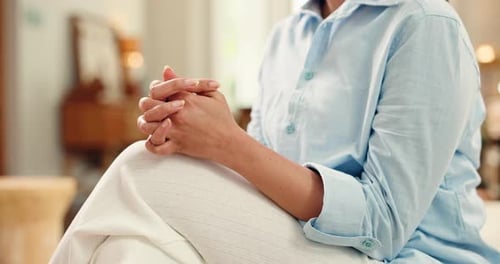 Woman Seated with Hands Clasped in Bright Room