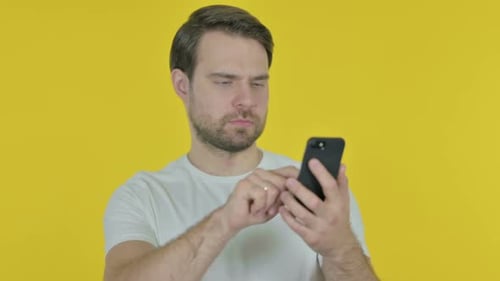 Young Adult Using Mobile Phone on Yellow Background