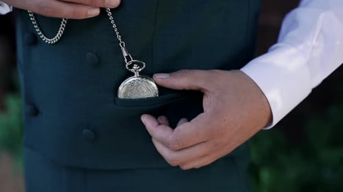 Silver Pocket Watch Placed into a Green Waistcoat Pocket