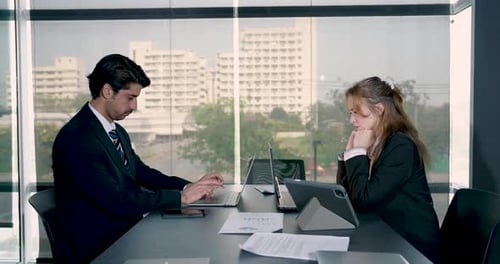 Two business professionals working on laptops during quiet office meeting. Focused teamwork and