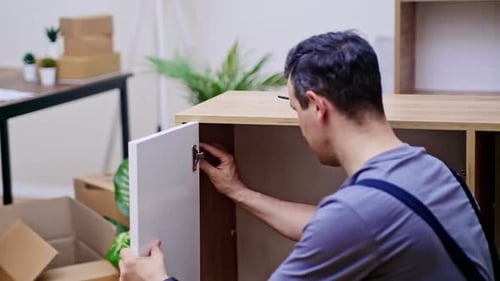 Furniture Delivery and Assembly Handyman Attaching White Door to Wooden Cabinet