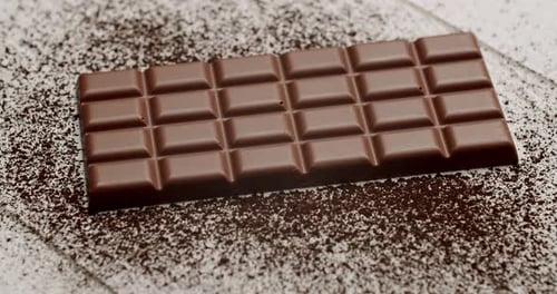 CloseUp Of A Chocolate Bar On Powdered Cocoa Background