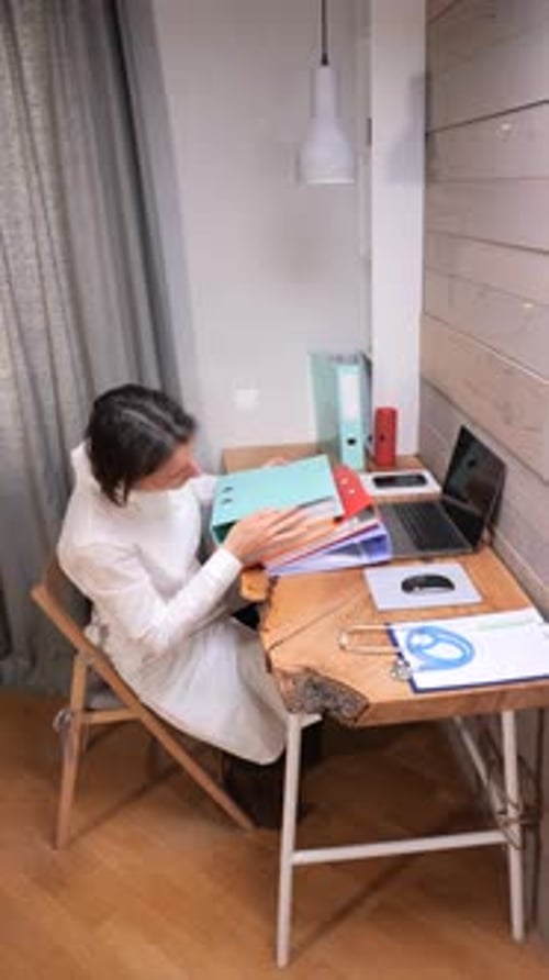 Vidéo verticale Femme médecin en blouse blanche organisant des dossiers médicaux et des dossiers sur un bureau en bois
