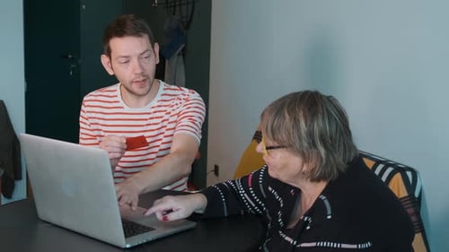 Young Adult Helping Senior with Online Purchase