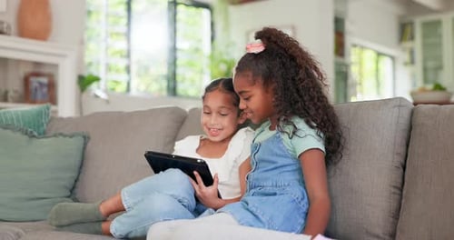 Two Girls Viewing Tablet Together on the Sofa
