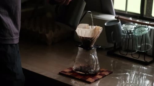 Pouring Water Into Coffee Filter in Kitchen