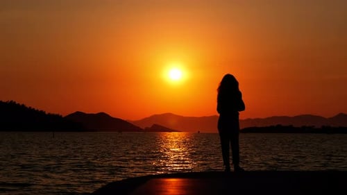 Silhouette eines Mädchens am Meer bei Sonnenuntergang