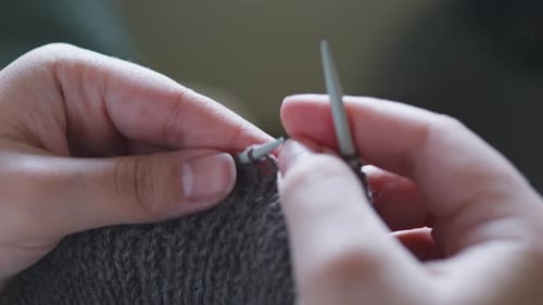 Hands Knit Gray Yarn with Needles in Close Up