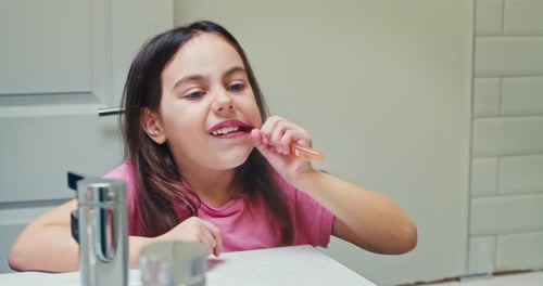 Little Girl Brushing Her Teeth with a Toothbrush in the Bathroom