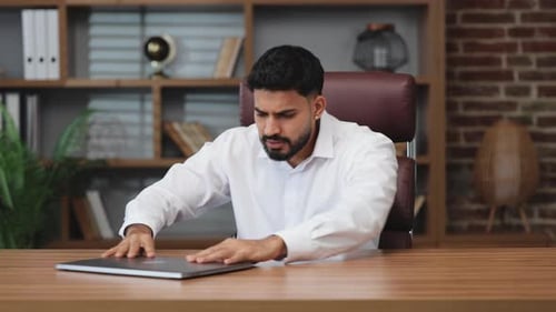 Frustrated Man Working on Laptop in Office