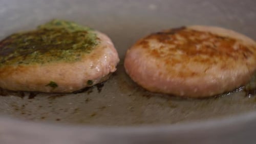 turning two hamburgers in a non stik pan with a skimmer - close up