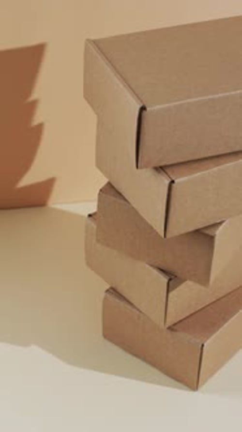 Vertical video of stacked cardboard boxes with copy space over brown background