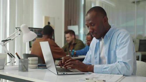 Portrait of Black Developer Posing at Office Desk with Laptop