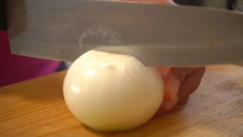 Slicing White Onion on Cutting Board with Knife