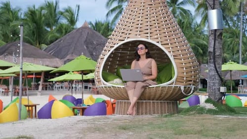 Young Woman Remotely Works on Laptop at Beach