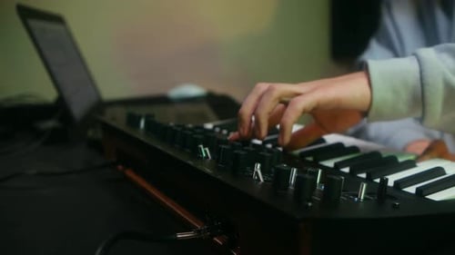 Hands Play a Keyboard Synthesizer in Home Studio