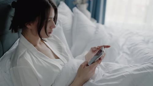 Woman Relaxing in Bed Using Smartphone