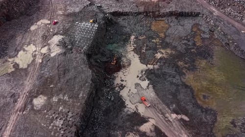 Workers extract granite from a quarry at an industrial site during the day