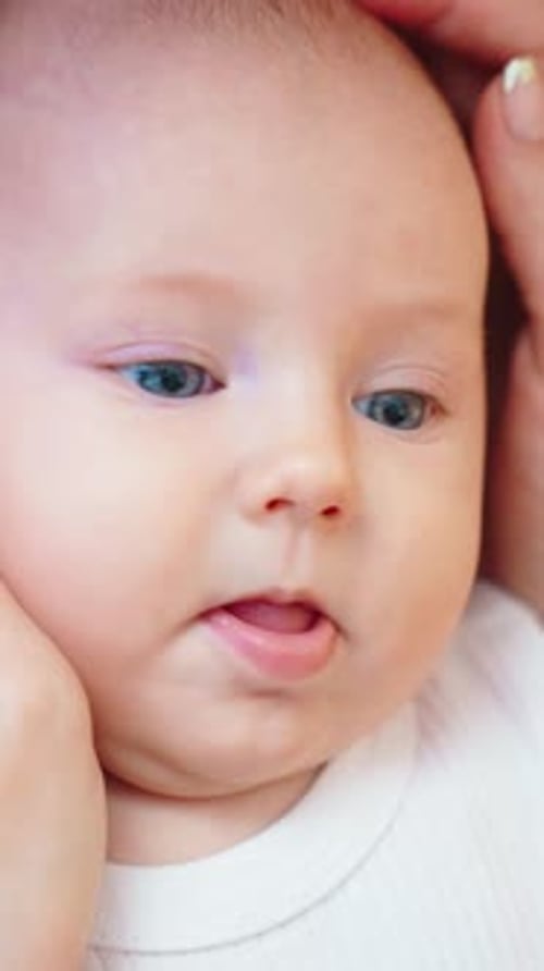Closeup of a Calm Baby Being Held Gently By a Caregiver Highlighting Serene Features and Captivating