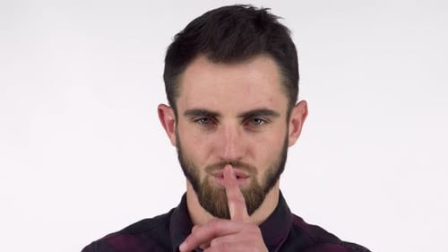 Bearded Man Playfully Shushing the Camera with a Finger to His Lips