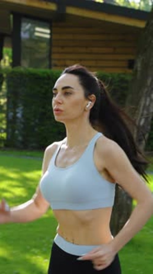 Vertical Screen Slow Motion Female Jogger with Earphones in Park