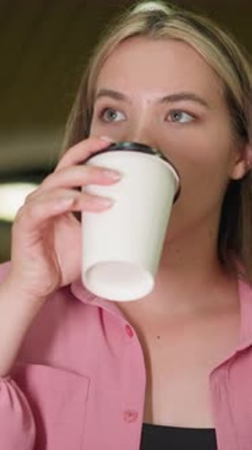 Lady in Pink Enjoys Coffee Sip with Satisfaction in Cozy Restaurant