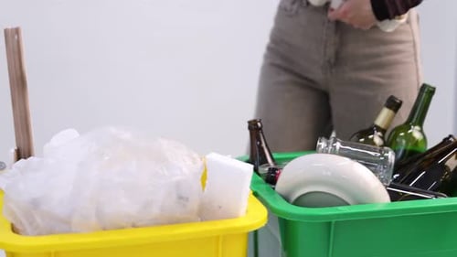 Woman Sorting Recycling Materials into Different Colored Bins