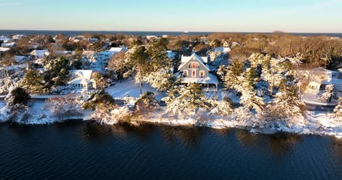 Homes on the lake in winter snow. Pretty aerial waterfront view.