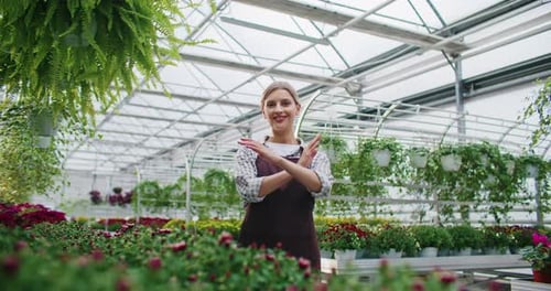 Smiling Woman Among Vibrant Flowers in Greenhouse