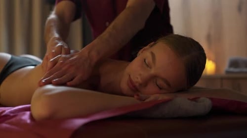 Spa Treatments Professional Masseur Makes a Relaxing Back Massage to a Young Woman Using Oils Female