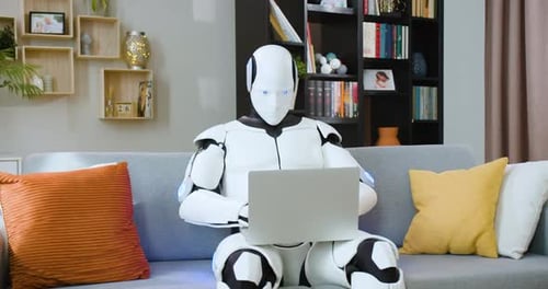 Concentrated Humanoid Robot Working on Wireless Laptop While Sitting on Comfortable Couch at Home