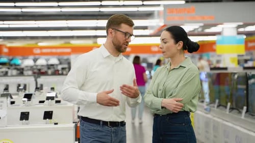 Seller Helping Young Woman Choosing Smartphone in Tech Store