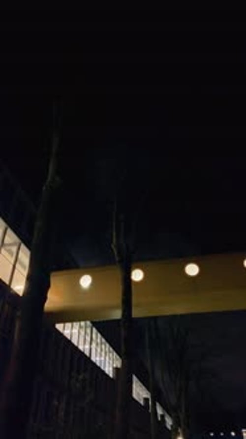 Illuminated Walkway Connecting Buildings at Night in Amsterdam Noord