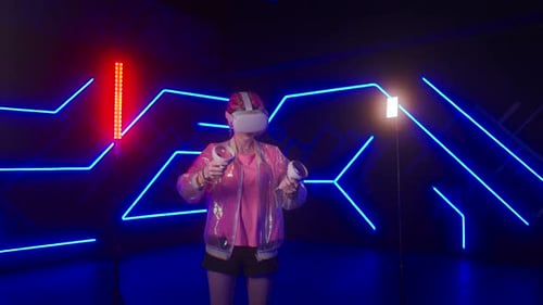 Young Female Gamer in Pink is Playing Virtual Reality Games VR Headset and Controllers