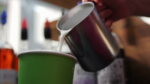 Employee Pours Hot Milk Into Cup with Coffee in Cafe Closeup