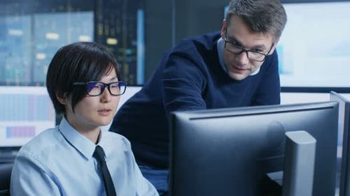 In the Data Mining Center Chief Statistician Consults His Young Assistant sits at His Workstation S