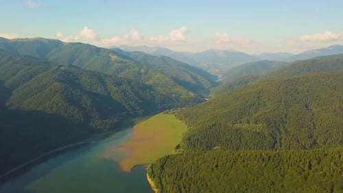 Aerial View of Big Lake with Clear Blue Water Between High Mountain Hills Covered with Dense