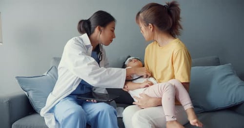 Doctor Examines Child on Couch with Mother