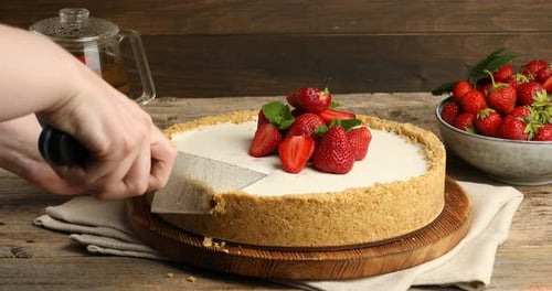 Cutting into strawberry cheesecake on rustic wood table